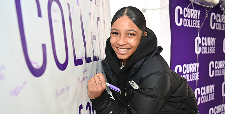 A student signs the class banner at Accepted Student Day