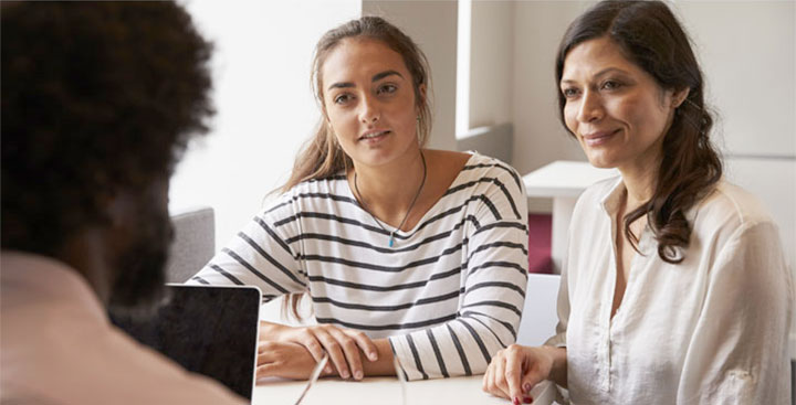 A mother and daughter discuss affordability with a counselor