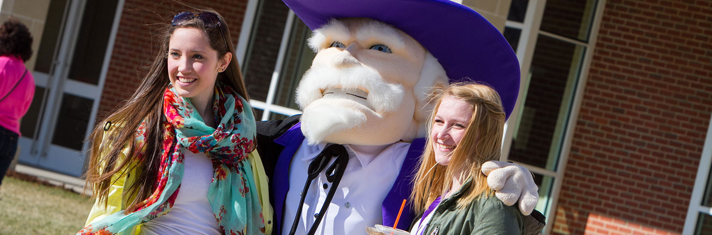 Two students pose for a picture with the Colonel at Curry College