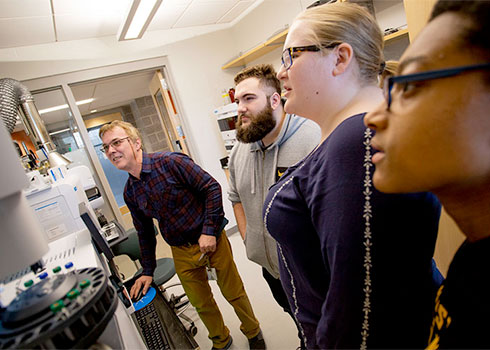 Dr. Sandor Kadar, lecturer in the department of science and math, with Curry College students