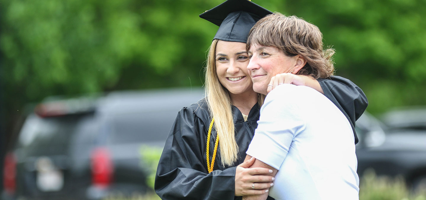 A Curry College student hugs her mom on Commencement