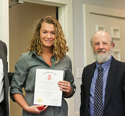 A member of Lambda Pi Eta poses for a photo during the induction ceremony