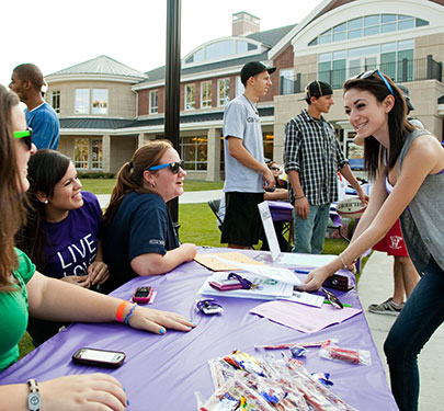 A student signs up at the Newman Club table during the Involvement Fair