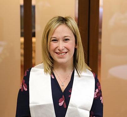 A Pi Lambda Theta member smiles at the camera during the induction ceremony