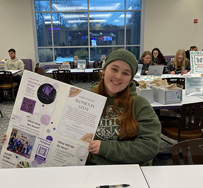 Curry female student examines subject in microscope