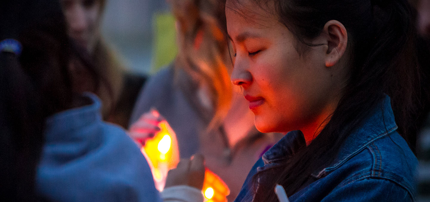 A student attends a candlelight vigil on campus