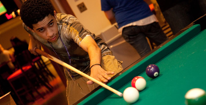 A student playing pool in the Billiards Room