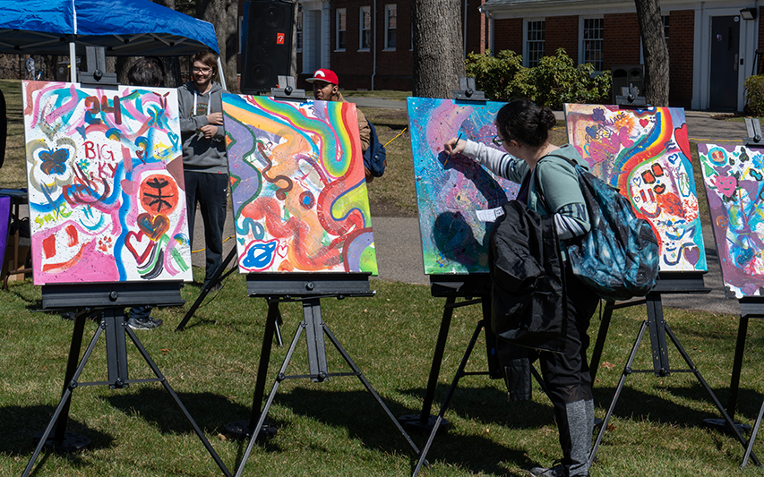 At the Counseling Center's Fresh Check Day 2023, a student paints on a canvas on the Quad.